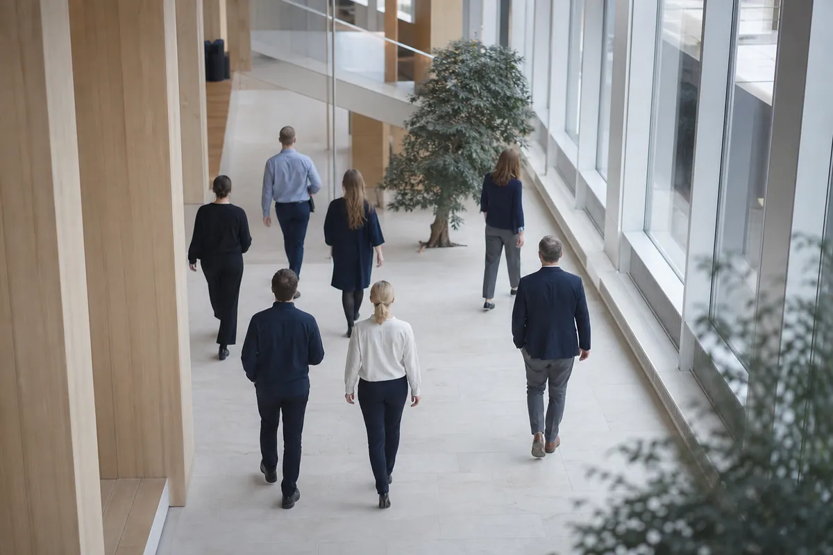 Människor i rörelse genom en ljus kontorsatriumhall sedd snett uppifrån